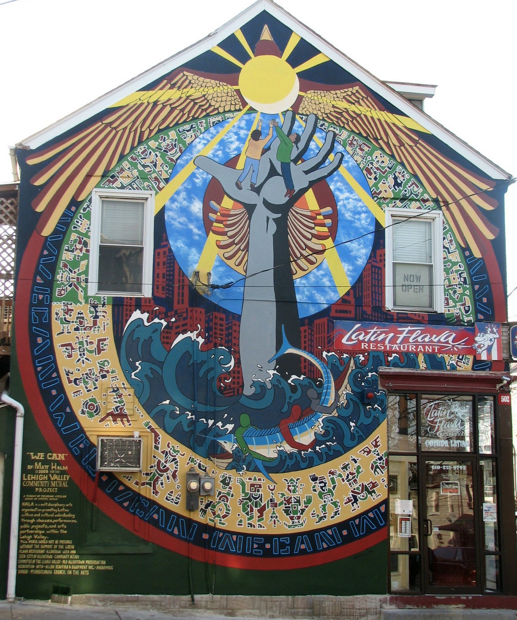 Photo of intricut mural with two people standing on a hand reaching towards the sun.