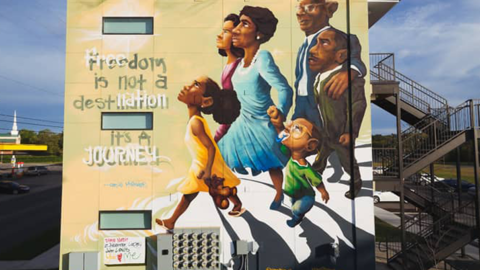 Mural of a family walking and looking up next to the words: Freedom is not a destination it's a Journey"