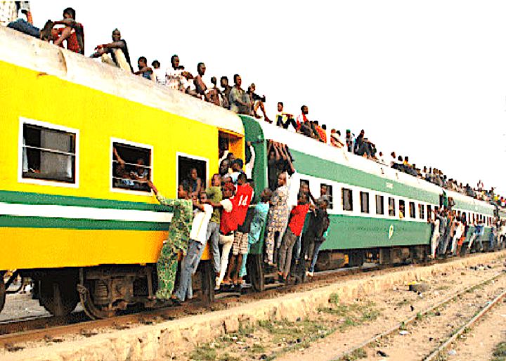 People sitting on top of a train and holding onto the sides