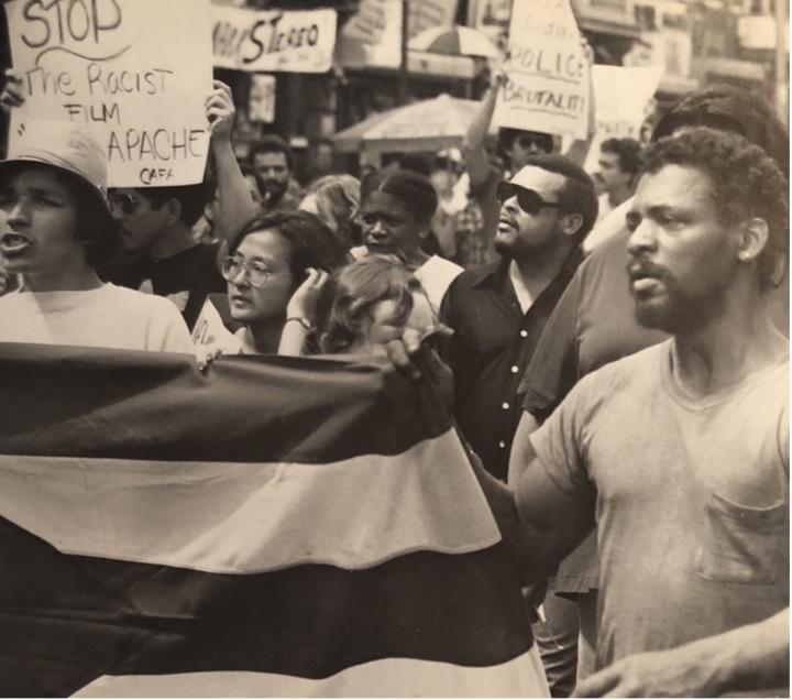 A rally organized by the Committee Against Fort Apache takes over a New York Street, with a multiracial group of protestors holding signs including, 'Stop the Racist Film Fort Apache.